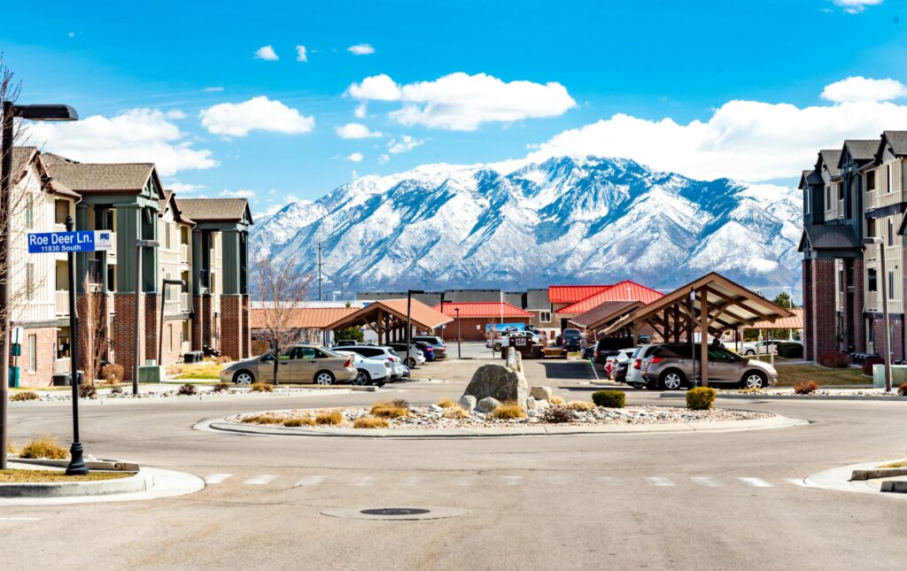 Parking lot in between apartment buildings with big mountains in the distance